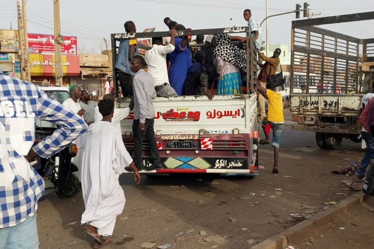 Persone che salgono sui camion per cercare di lasciare il nord di Khartoum.