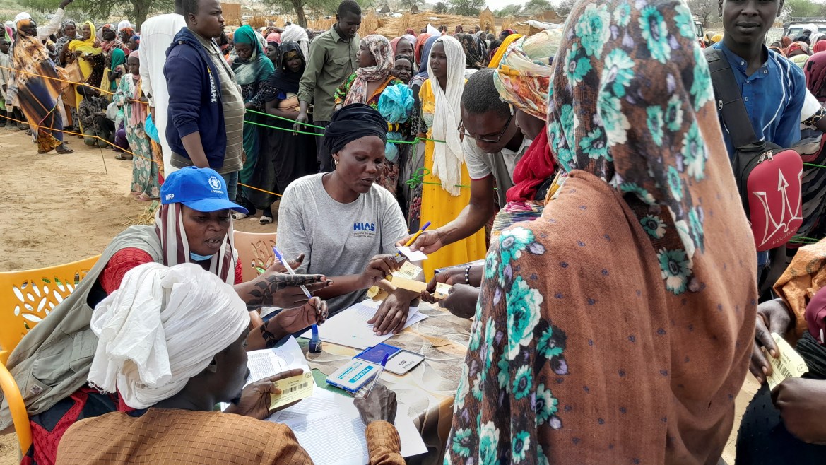 Sudanese refugees who have fled the violence in their country queue to receive food supplements from World Food Programme (WFP) near the border between Sudan and Chad in Adre,