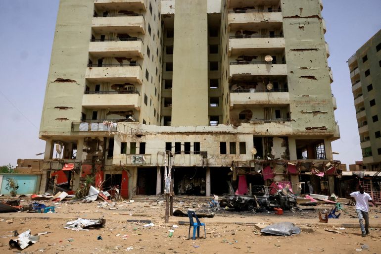 A man walks near a damaged car and buildings at the central market during clashes between the paramilitary Rapid Support Forces and the army in Khartoum North, Sudan April 27, 2023. REUTERS/ Mohamed Nureldin Abdallah