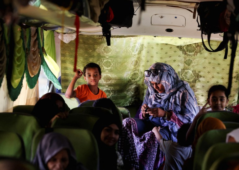 Sudan'dan kaçan yolcular, Hartum'dan Mısır'ın Aswan kentindeki Nil Nehri'nin yukarı kesimlerindeki Ebu Simbel şehrine tahliye edildikten sonra Argeen kara limanına vardıklarında bir aile otobüste oturuyor.