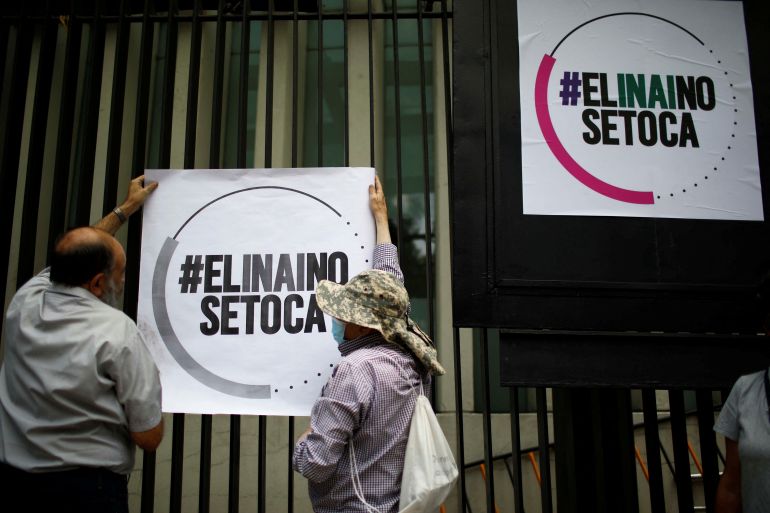 Two people lift up a banner onto a wall that reads "#ELINAINO SETOCA"