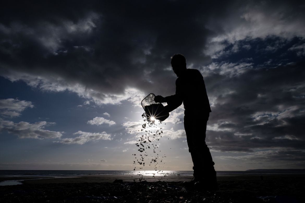 A volunteer pours the contents of a bucket full of nurdles