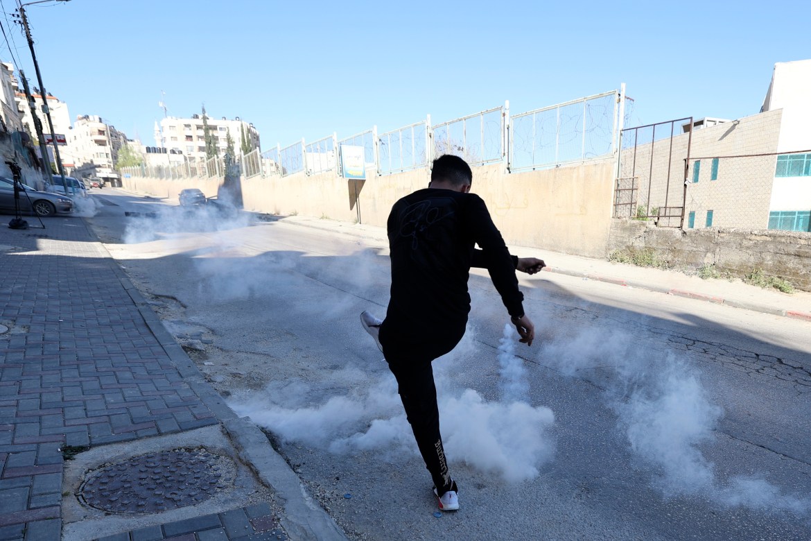 A Palestinian kicks a teargas canister