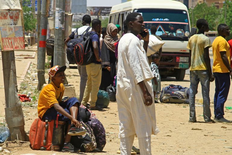 People wait for a bus to flee from southern Khartoum on April 18, 2023 as fighting between the army and paramilitary forces led by rival generals rages for a fourth day