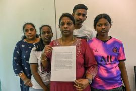 Leelavathy Suppiah, the sister of Tangaraju Suppiah who was convicted of drug trafficking in Singapore and set to be hanged on Wednesday, is holding a letter appealing for clemency to Singapore's president. She is surrounded by other family members.