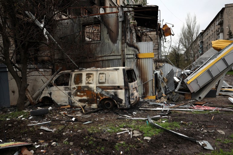 This photo, taken on April 23, 2023, shows a wrecked vehicle near a shelling-damaged residential building in the frontline city of Bakhmut