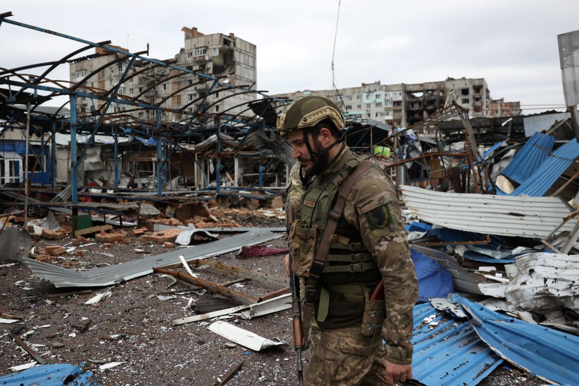 A Ukrainian serviceman walks near residential buildings damaged by shelling in the frontline city of Bakhmut