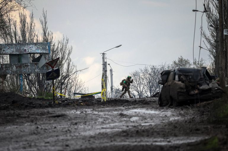 A Ukrainian serviceman runs for cover from shelling across a street in the frontline town of Bakhmut