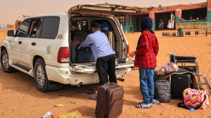 Passengers take out luggage as they disembark from a vehicle at a rest point by a desert road at al-Gabolab in Sudan's Northern State, about 100 kilometres northwest of the capital, on April 25, 2023.