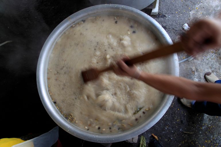 A big pot of Bubur Lambuk, a sweet-savoury rice porridge. It s a creamy colour and a man is stirring the gargantuan pot.