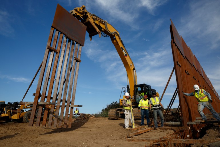 Construction workers and equipment install a border wall near Tijuana, Mexico