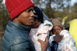 Haitian migrant Gerson Solay, 28, carries his daughter, Bianca, as he and his family cross into Canada at the non-official Roxham Road border crossing north of Champlain, N.Y., on Friday, March 24, 2023. A new US-Canadian migration agreement closes a loophole that has allowed migrants who enter Canada away from official border posts to stay in the country while awaiting an asylum decision. (AP Photo/Hasan Jamali)