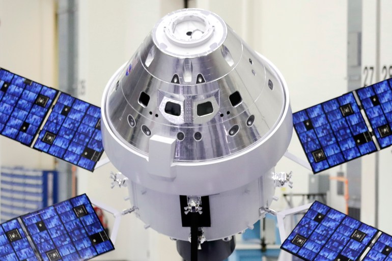 A silver space capsule with four blue panels emanating from the base