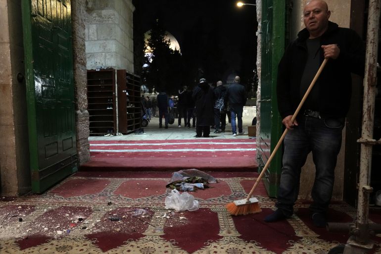 A Palestinian worshipper sweeps debris after a raid by Israeli police at the Al-Aqsa Mosque