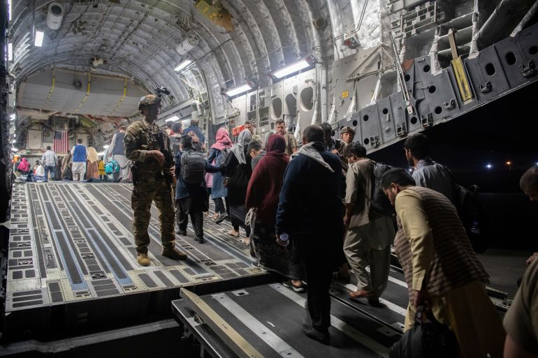 People walk up a ramp to enter a military plane