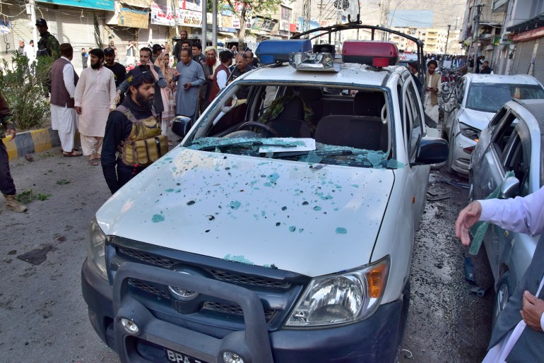 Police officers examine a damaged police vehicle at the site of bomb blast, in Quetta, Pakistan, Monday, April 10, 2023. A roadside bomb targeting a police vehicle in volatile southwestern Pakistan on Monday killed few people and wounded more than dozen others, mostly civilian pedestrians, a government spokesperson said. (AP Photo/Arshad Butt)