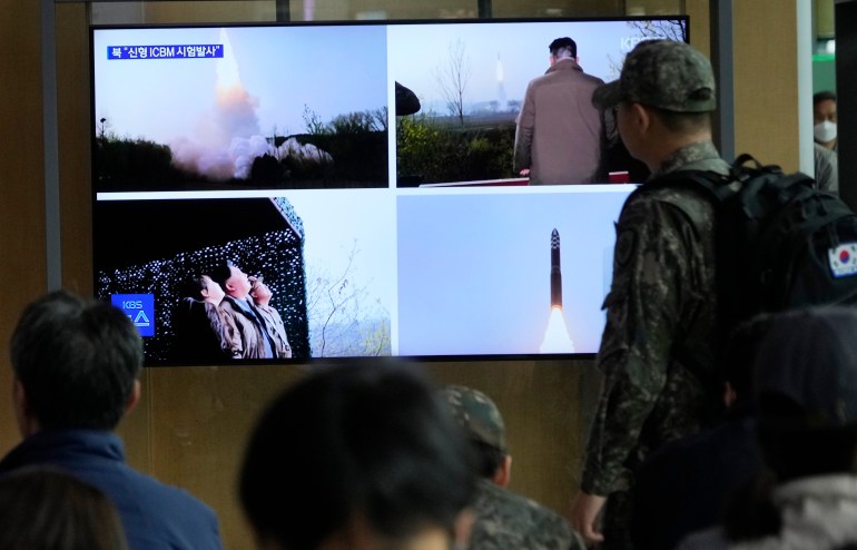 Persone che guardano un notiziario sudcoreano sul lancio nordcoreano.  Sullo schermo ci sono quattro immagini diffuse dai media statali.
