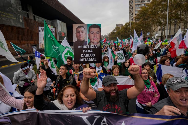 Protesters and relatives of police officers who were killed in the line of duty take part in a march called by their relatives amid an increase in violent crime, in front of the La Moneda presidential palace.