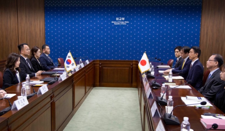Japanese and South Korean officials sit across from each other during a meeting