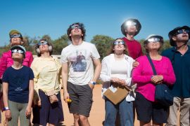 People in Exmouth wearing protective glasses as they look up to the sky to watch the total eclipse
