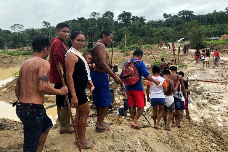 Sederet orang berbaris ke bawah menuju bentangan hutan hujan Amazon yang berlumpur dan gundul.