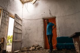 Man stands in the middle of a room that has been damaged by a missile attack