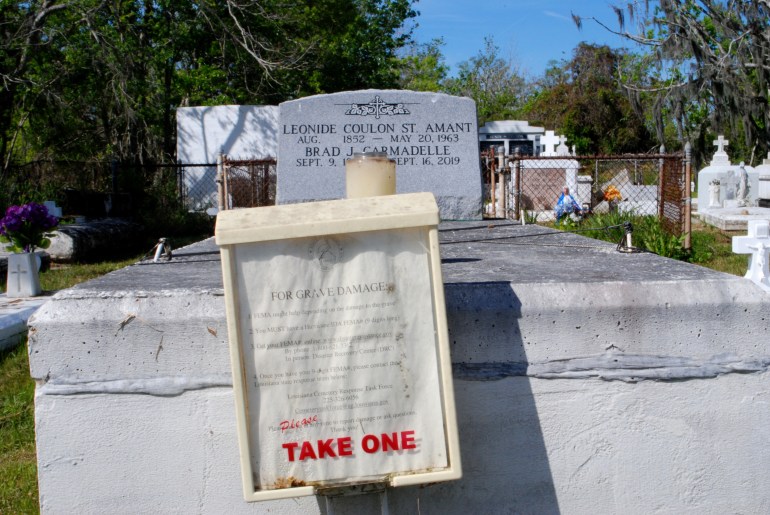 A photo of a sign that says "For Grave Damage" and "take one" on the plastic container housing it.
