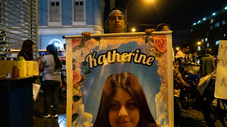 A woman holds up a poster that reads: "Catherine"and contains the portrait of a teenage girl