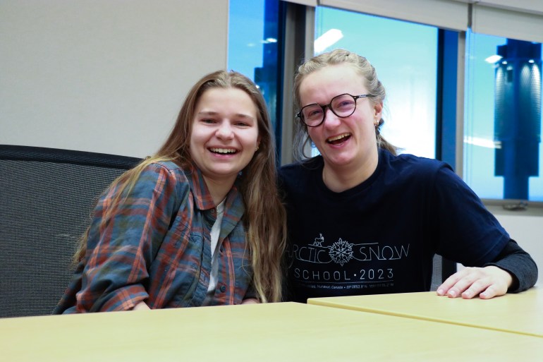 Dua siswa tertawa bersama di Sekolah Salju Arktik