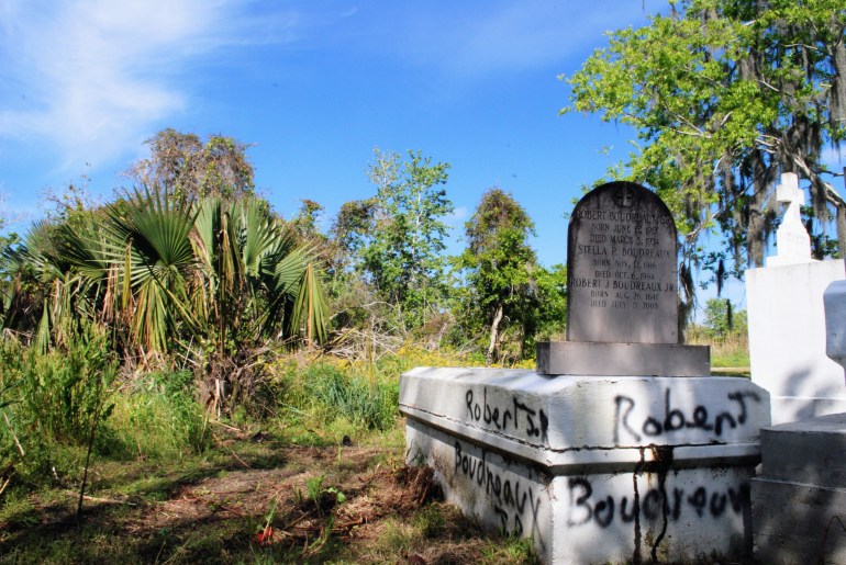 A photo of a gravestone with the name "Robert Boudreaux" spray-painted on both the left and back side.