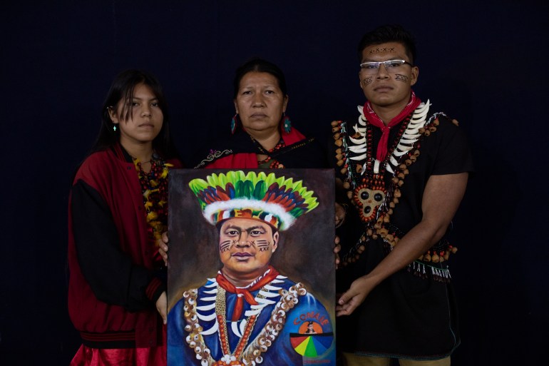 Une femme avec deux enfants de chaque côté d'elle tient un portrait peint d'Eduardo Mendúa