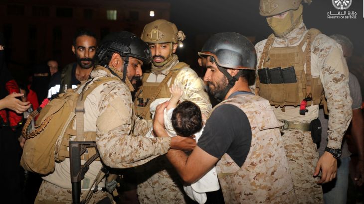 Saudi Royal Navy officers assist a child aboard their navy ship as they evacuate Saudis and other nationals from Sudan to escape the conflict.
