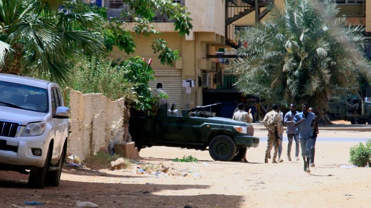 People walk past a military vehicle in Khartoum on Saturday