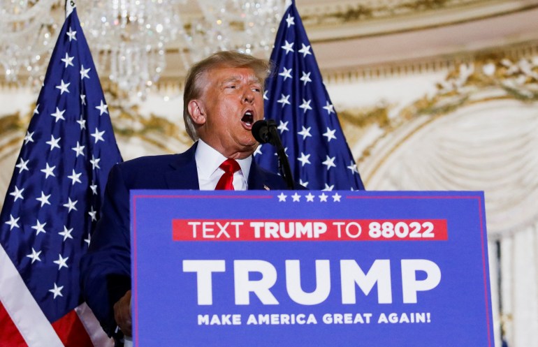 Trump di podium yang bertuliskan: "SMS Trump ke 88022, Trump, Jadikan Amerika Hebat Lagi"