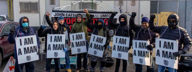 A photo of Andre Soleyn and colleagues with sings hanging around their necks with the words "I Am A Man"