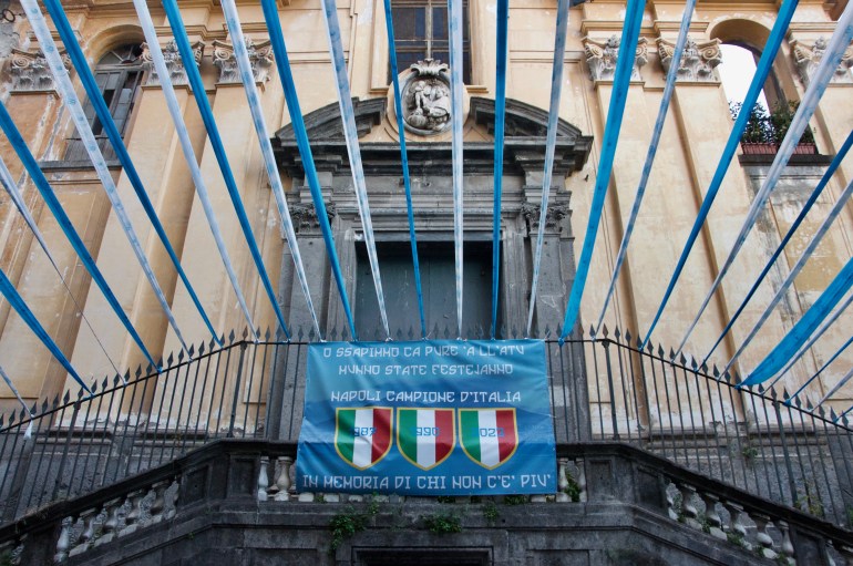 A banner outside a church in the Salvator Rosa neighborhood reads in the Neapolitan language: “And we know that even on the other side of the world, you all will be celebrating.”