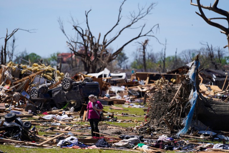 A woman walks amid debris from extreme storms