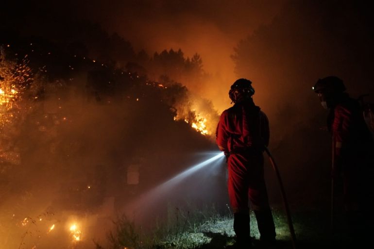A handout photo made available by Spanish Defense Ministry shows firefighters trying to extisguish a fire at the villages of Cadalso, Descargamaria and Robledillo de Gata, in the area of Sierra de Gata, Caceres, Extremadura