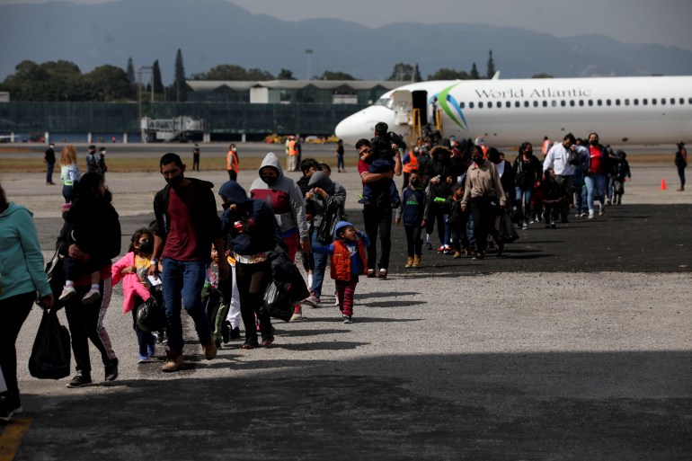 Guatemalan deportees cross the tarmac after arriving on a deportation flight from the US, at the Guatemalan Air Force