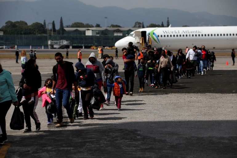 Deportados guatemaltecos cruzan la pista después de llegar en un vuelo de deportación desde los EE. UU., en la Fuerza Aérea de Guatemala