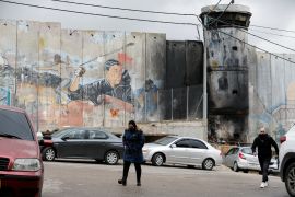 Palestinians walk in front of a section of the Israeli barrier in Aida refugee camp, in Bethlehem, in the Israeli-occupied West Bank, February 1, 2022.