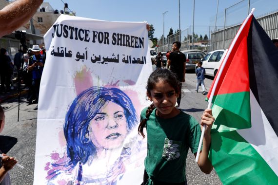 Girl holds Palestinian flad and poster featuring Shireen Abu Akleh