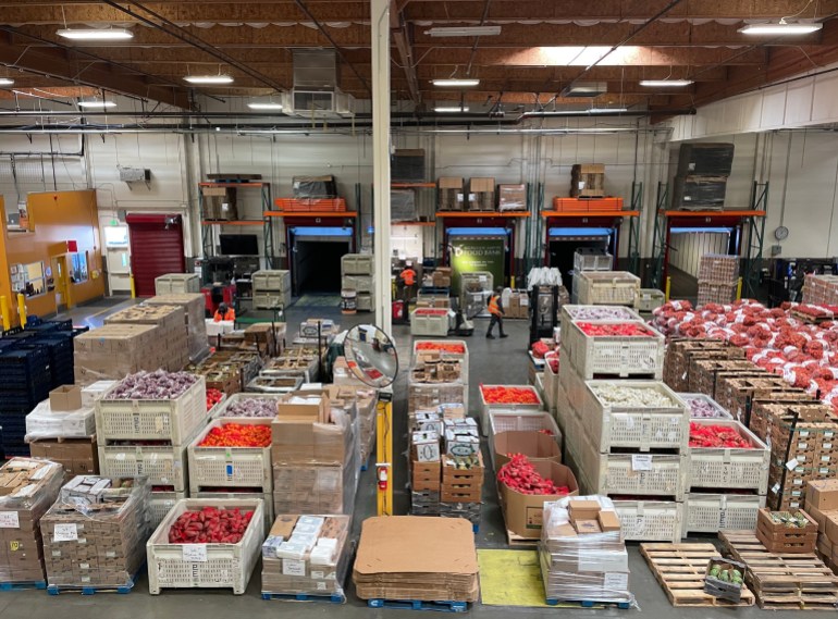 A warehouse in California filled with food crates, including large crates of fresh produce.