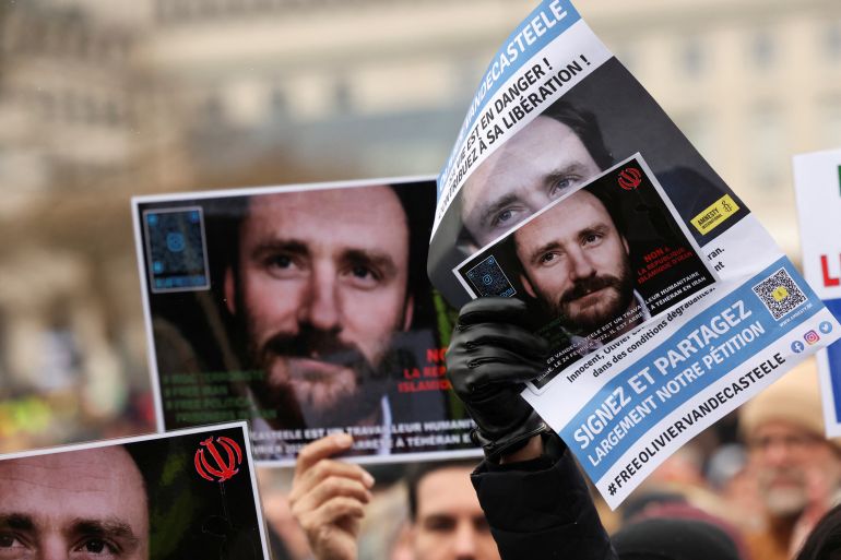 People hold pictures of Belgian aid worker Olivier Vandecasteele during a protest