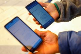 Migrants from Venezuela hold out cell phones with the CBP One app