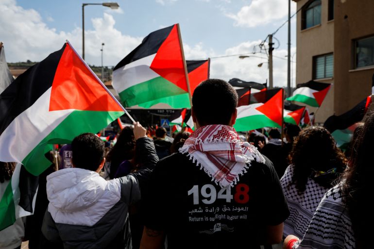 Israeli Arabs hold Palestinian flags as they take part in a "Land Day" rally, an annual commemoration of the killing of six Arab citizens by Israeli security forces in 1976 during protests against land confiscations, in Sakhnin in northern Israel March 30, 2023. REUTERS/Ammar Awad