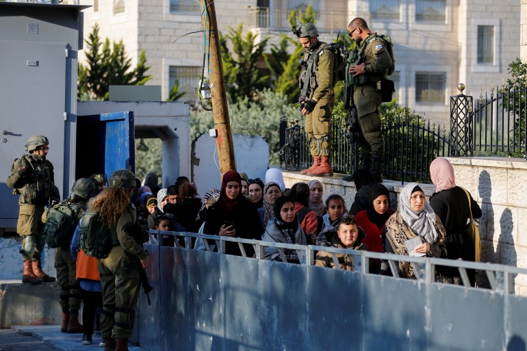 Palestinos passam por um posto de controle israelense a caminho da mesquita de Al-Aqsa, em Jerusalém