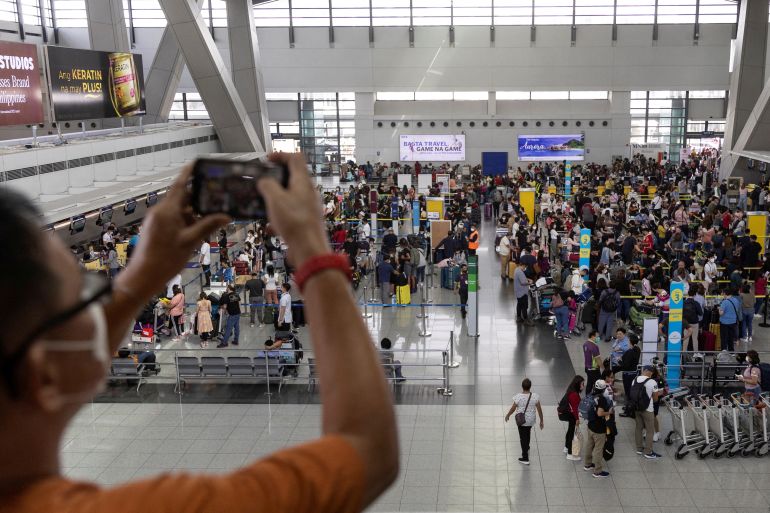 A man takes a picture of passengers queueing at the Ninoy Aquino International Airport, in Pasay City, Metro Manila, Philippines, January 2, 2023