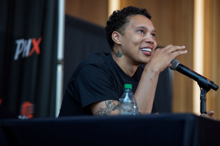 Brittney Griner smiles at a microphone during a news conference