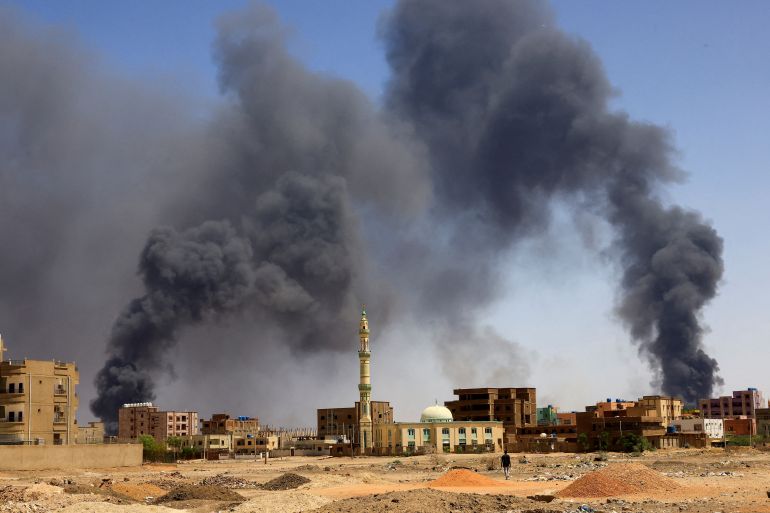A man walks while smoke rises above buildings after aerial bombardment in Khartoum North, Sudan, May 1, 2023.